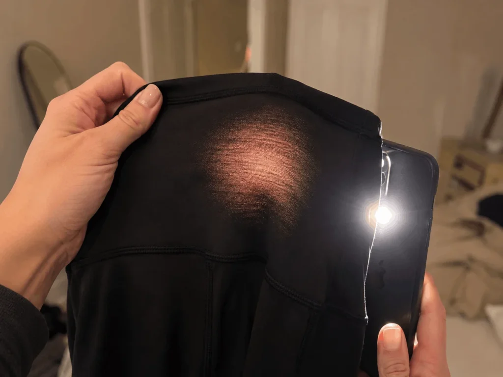 Phone flashlight held behind workout leggings fabric to check for see-through spots