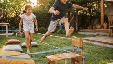 Two children aged 5–9 laughing and playing on a homemade backyard obstacle course, with tape lines and cushions on the grass in warm golden afternoon sunlight, promoting active outdoor play and family fun